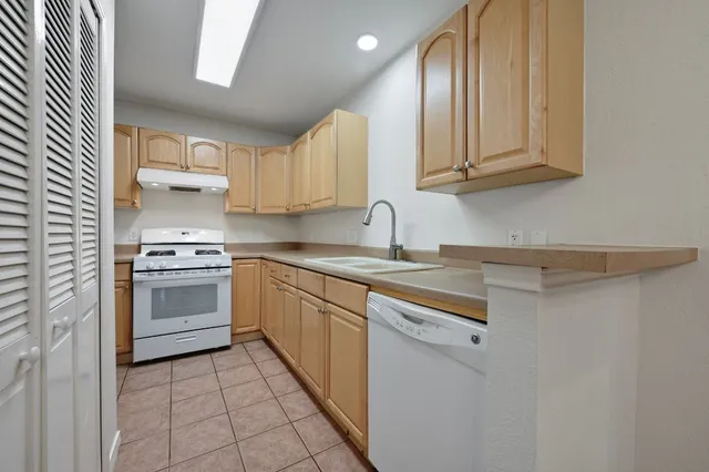 a kitchen with stainless steel appliances granite countertop a sink and dishwasher a stove top oven with white cabinets