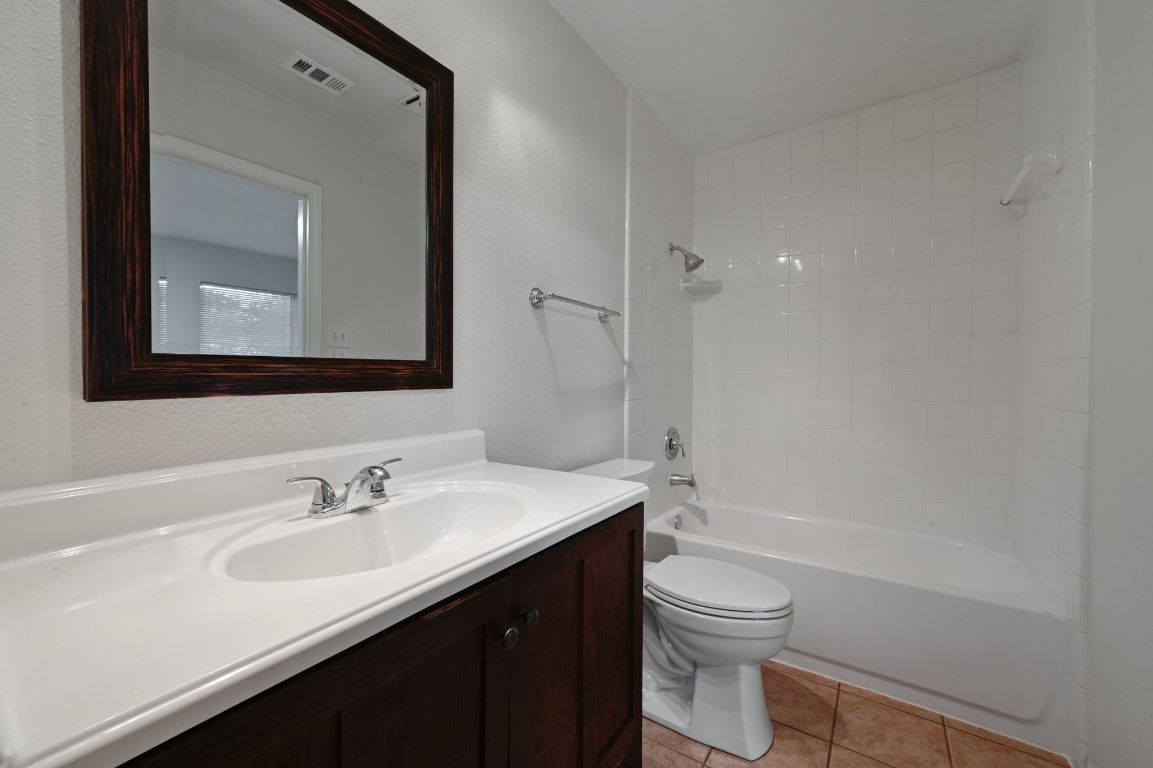 9711 Curlew Drive Austin, TX 78748 - Photo 16 of 21 a bathroom with a toilet a sink a tub and a mirror