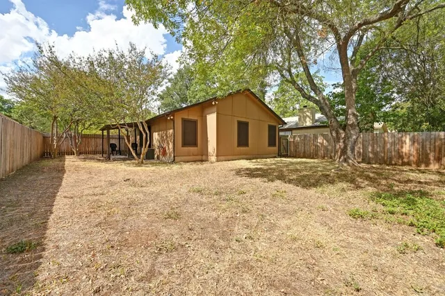a backyard with a tree and wooden fence