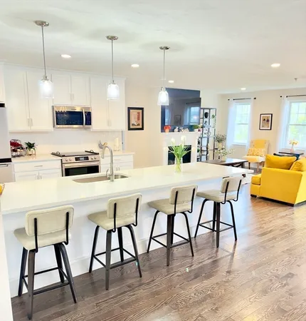 a kitchen with stainless steel appliances kitchen island granite countertop a dining table chairs and a refrigerator