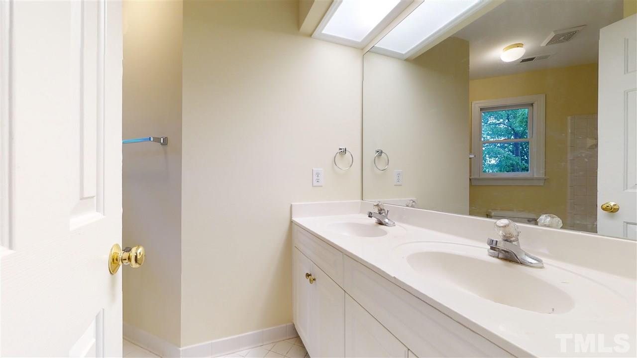9509 Brimstone Lane Raleigh, NC 27613 - Photo 23 of 30 Hall Bathroom has double bowl vanity, tub, ceramic tile floors, tub, water closet and window overlooking back yard.