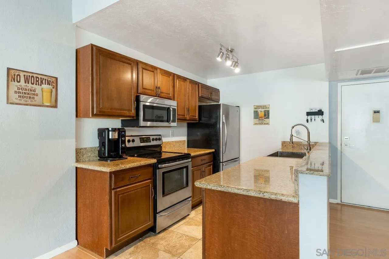 6191 Rancho Mission Road, Unit 308 San Diego, CA 92108 - Photo 2 of 31 a kitchen with stainless steel appliances granite countertop a stove top oven a sink dishwasher and a refrigerator