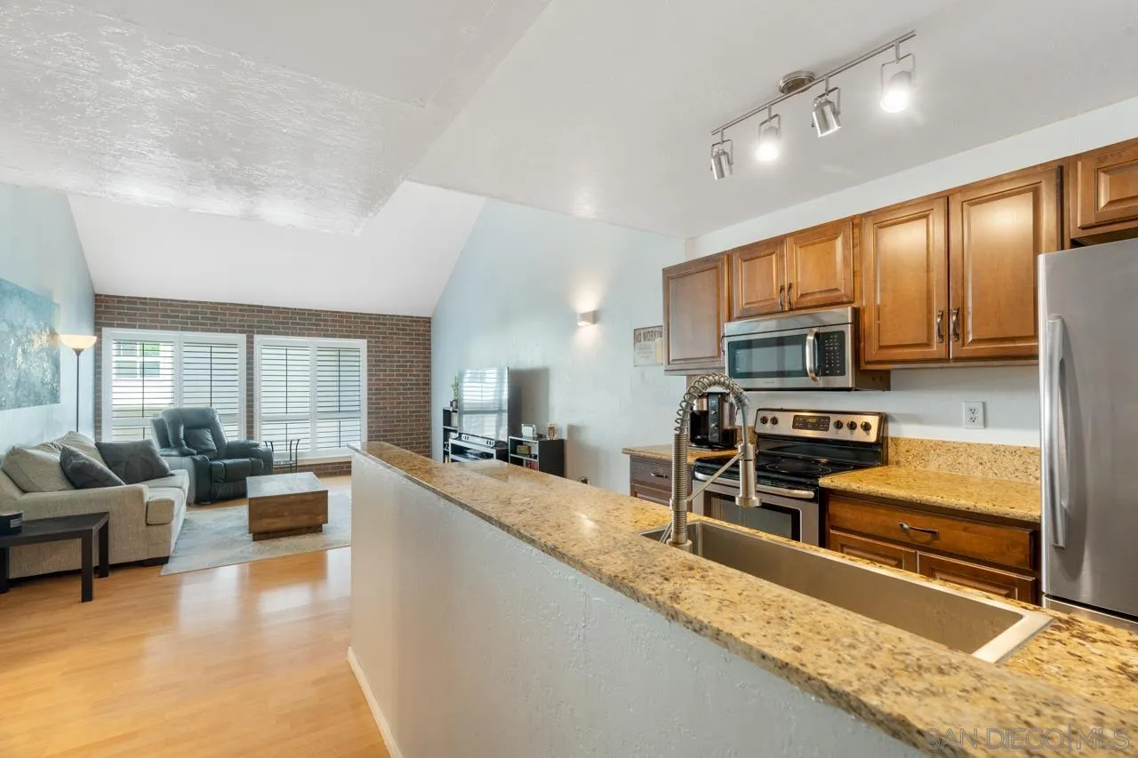 6191 Rancho Mission Road, Unit 308 San Diego, CA 92108 - Photo 7 of 31 a large kitchen with stainless steel appliances a stove a sink a oven with a dining table and chairs