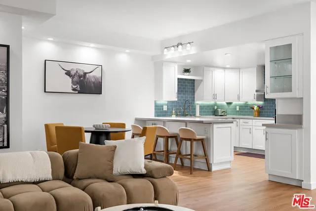 a living room with furniture kitchen view and a wooden floor