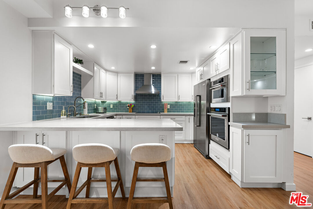 321 South San Vicente Boulevard, Unit 507 Los Angeles, CA 90048 - Photo 6 of 30 a kitchen with stainless steel appliances a table chairs refrigerator and cabinets