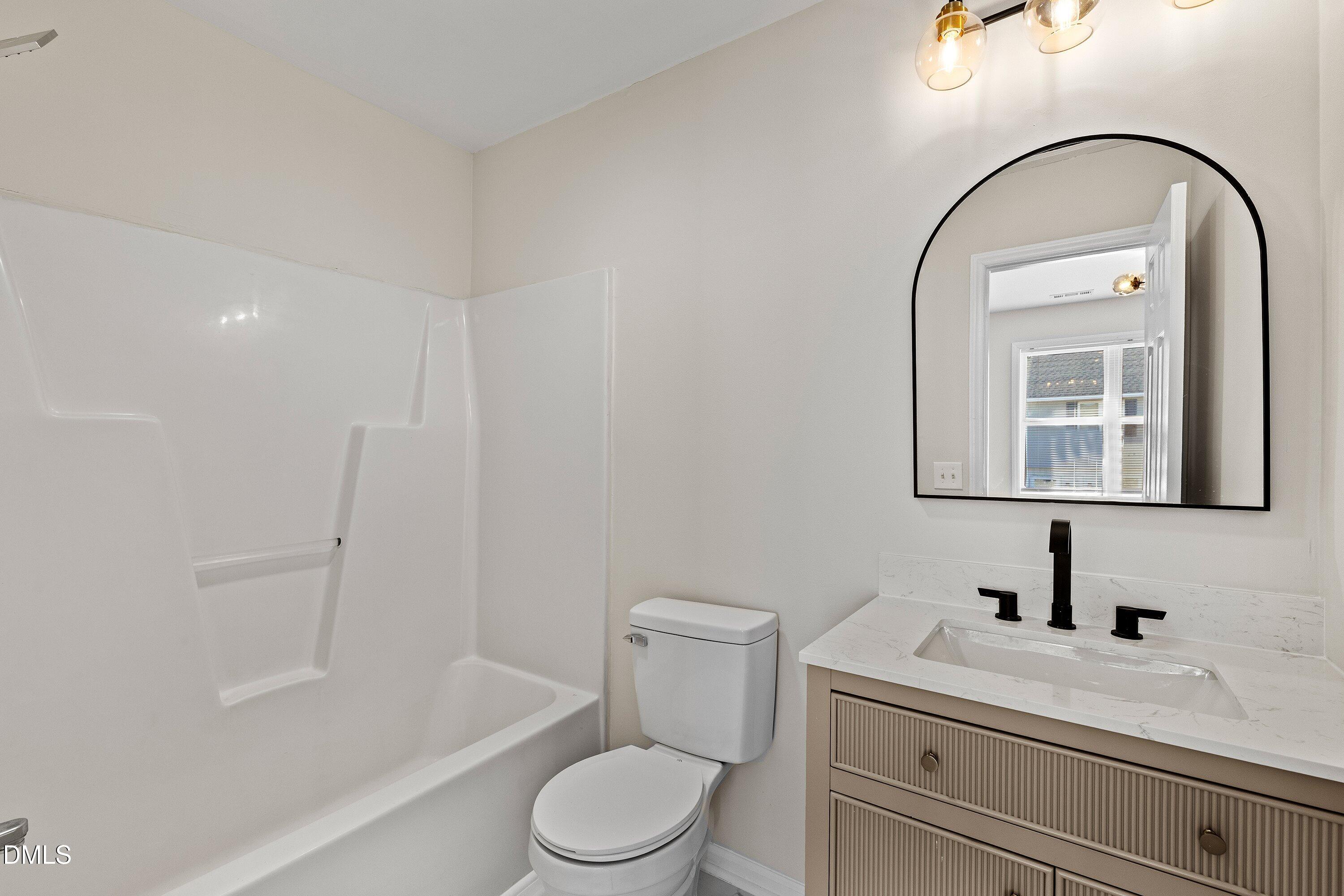 389 East Williams Street Angier, NC 27501 - Photo 18 of 26 a bathroom with a toilet a sink a mirror a bathtub and vanity