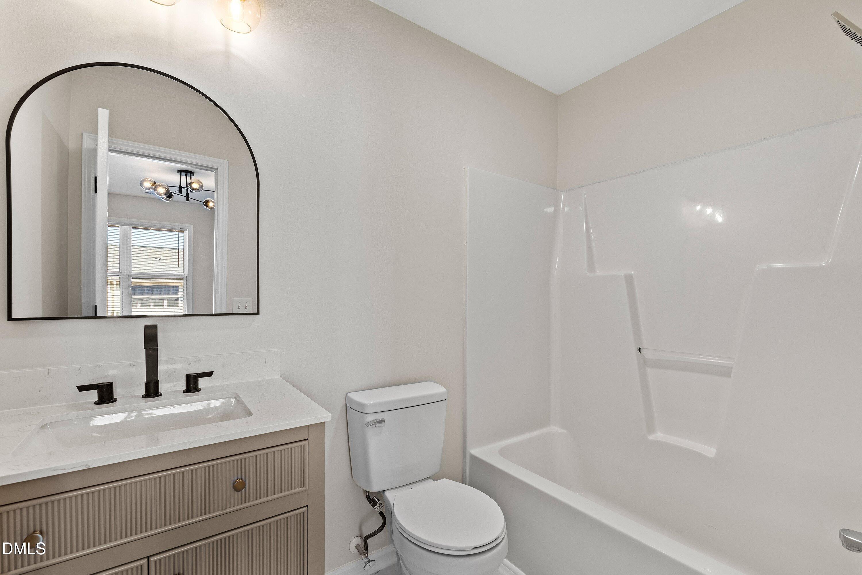 389 East Williams Street Angier, NC 27501 - Photo 21 of 26 a bathroom with a toilet a sink a bath tub and mirror