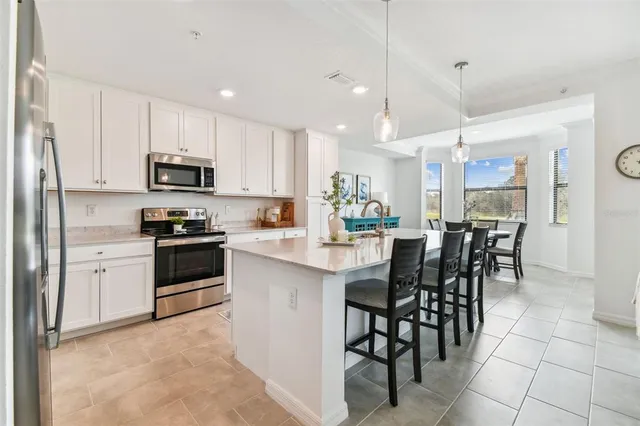 a kitchen with stainless steel appliances granite countertop a stove a sink a microwave a dining table and chairs