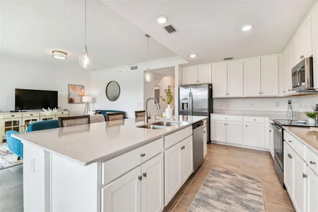 a kitchen with stainless steel appliances granite countertop a sink dishwasher a refrigerator and a oven with white cabinets