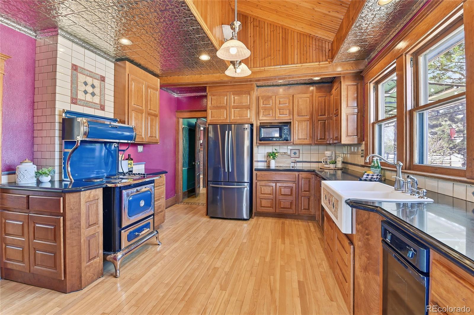 9490 Spruce Mountain Road Larkspur, CO 80118 - Photo 10 of 49 a kitchen with stainless steel appliances granite countertop a refrigerator a sink dishwasher a stove and white countertops with wooden floor