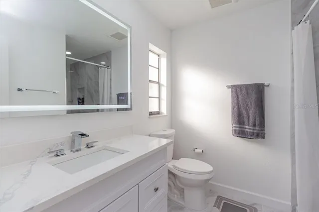 a bathroom with a toilet a sink a mirror and a window