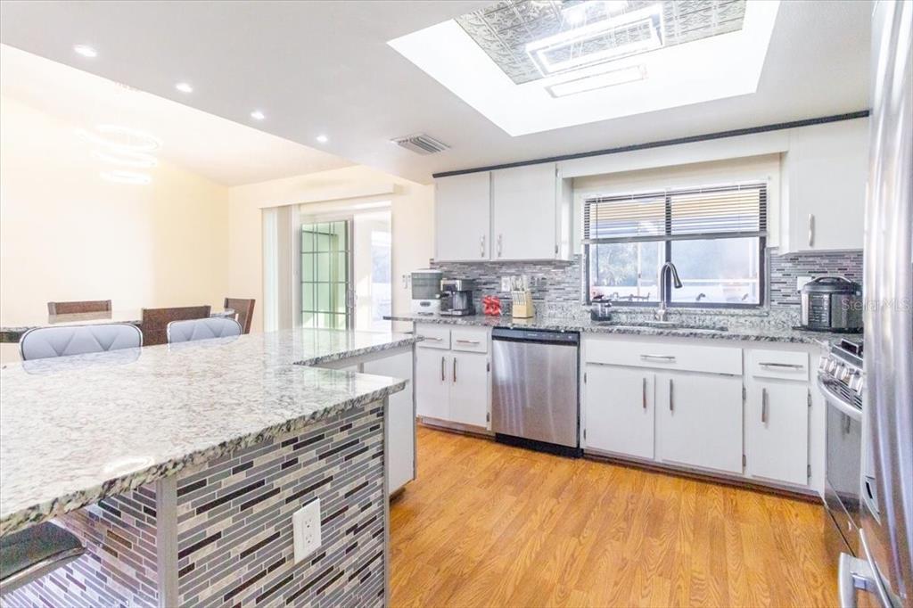7264 Lindhurst Street Spring Hill, FL 34606 - Photo 22 of 24 a kitchen with granite countertop a stove a sink and white cabinets