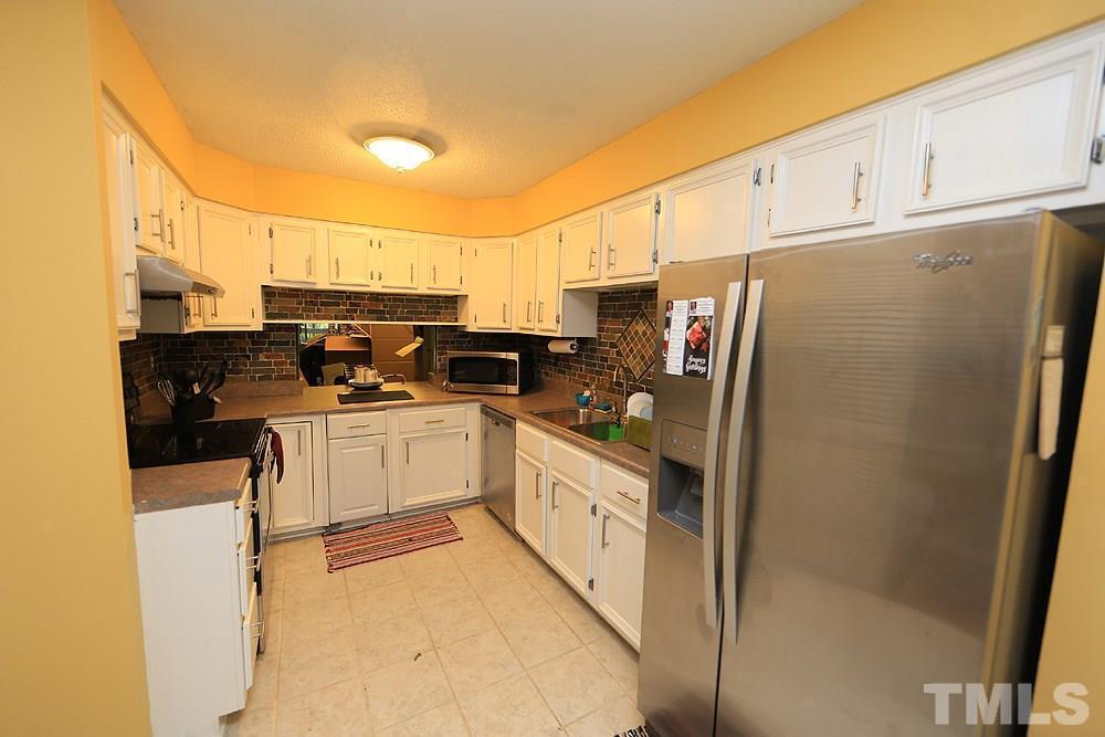 4100 Five Oaks Drive, Unit 49 Durham, NC 27707 - Photo 8 of 23 a kitchen with stainless steel appliances a refrigerator a stove a sink and white cabinets