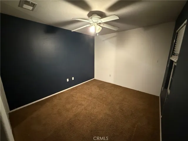 an empty room with a chandelier fan and a window