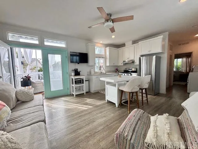 a living room with stainless steel appliances furniture and a kitchen view