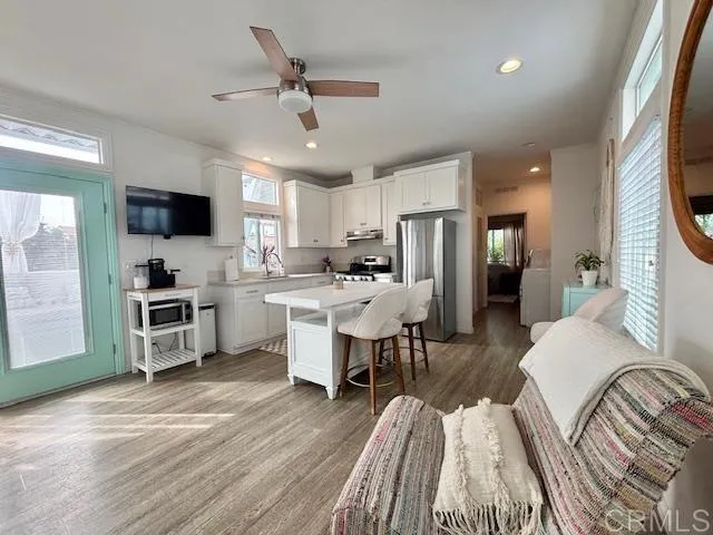 a living room with stainless steel appliances furniture and a flat screen tv