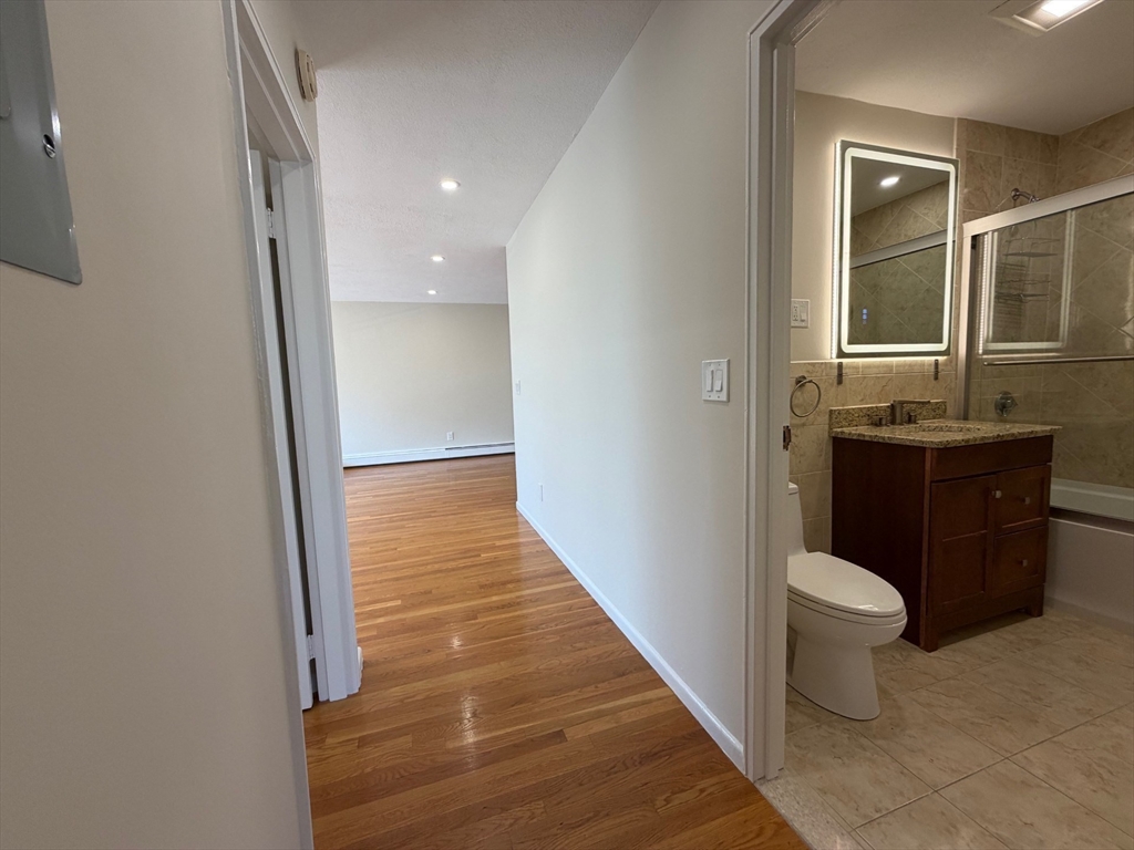 383 Langley Road, Unit 11 Newton, MA 02459 - Photo 12 of 15 a bathroom with a granite countertop sink and a toilet