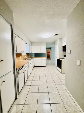 a large white kitchen with stainless steel appliances granite countertop a refrigerator and a stove top oven