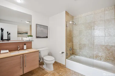 a bathroom with a toilet a sink a mirror a bathtub and shower