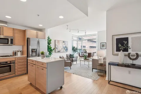 a open kitchen with stainless steel appliances kitchen island granite countertop a sink dishwasher stove top oven and cabinets with wooden floor