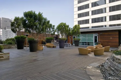 a view of a patio with couches chairs potted plants and wooden floor