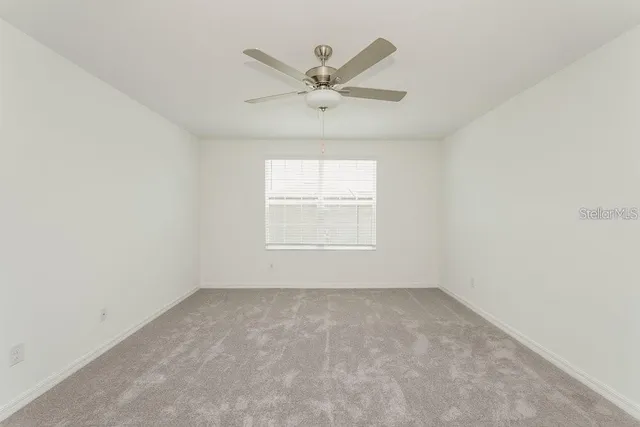 an empty room with a window and a fan
