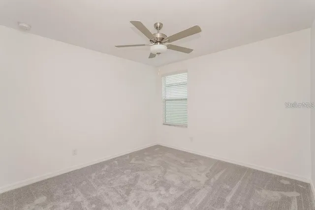 an empty room with window and ceiling fan