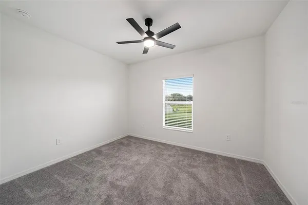 an empty room with a ceiling fan and window