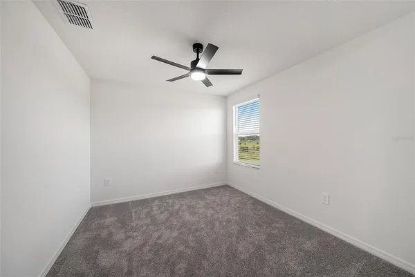 an empty room with a window and a fan