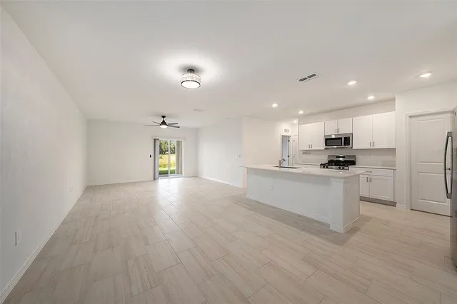 a view of kitchen with refrigerator and white cabinets