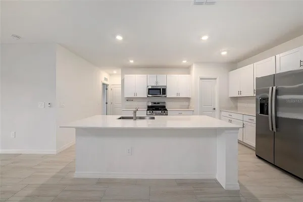 a view of kitchen with stainless steel appliances granite countertop a sink a stove a refrigerator and a refrigerator