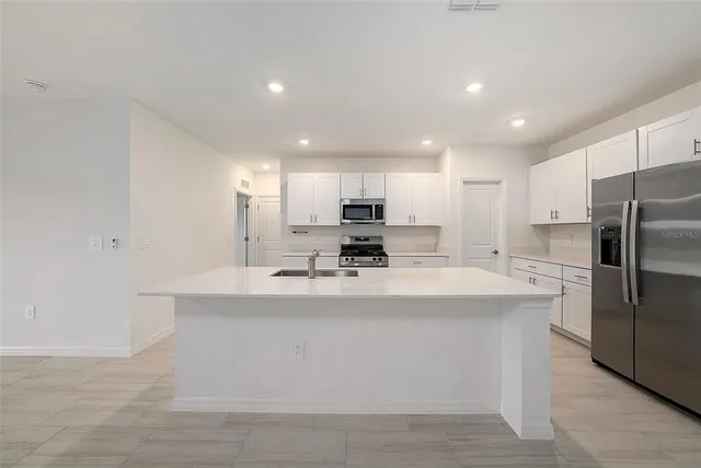 a view of kitchen with stainless steel appliances granite countertop a sink a stove a refrigerator and a refrigerator