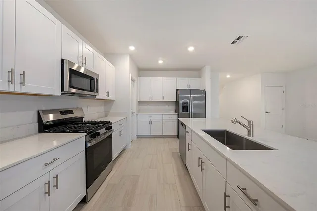 a large kitchen with stainless steel appliances granite countertop a sink a stove and a refrigerator