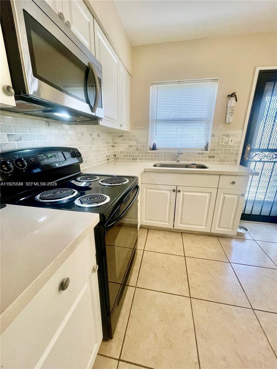 1064 Southwest 2nd Street, Unit 1 Hallandale Beach, FL 33009 - Photo 3 of 14 a kitchen with stainless steel appliances granite countertop a stove a sink and a microwave