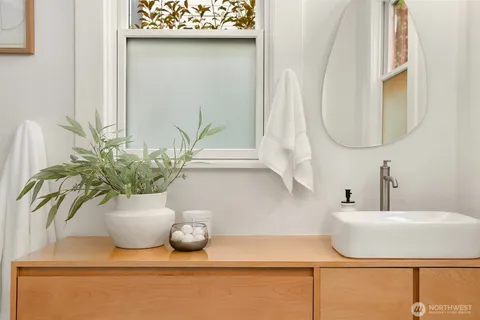 a bathroom with a sink a mirror and a potted plant