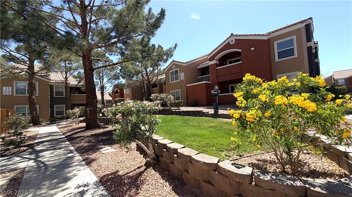 8101 West Flamingo Road, Unit 1082 Las Vegas, NV 89147 - Photo 15 of 23 A row of apartment buildings with Mediterranean-inspired architecture is bordered by vibrant landscaping.