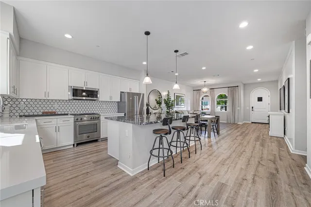 a kitchen with stainless steel appliances a dining table chairs stove and cabinets