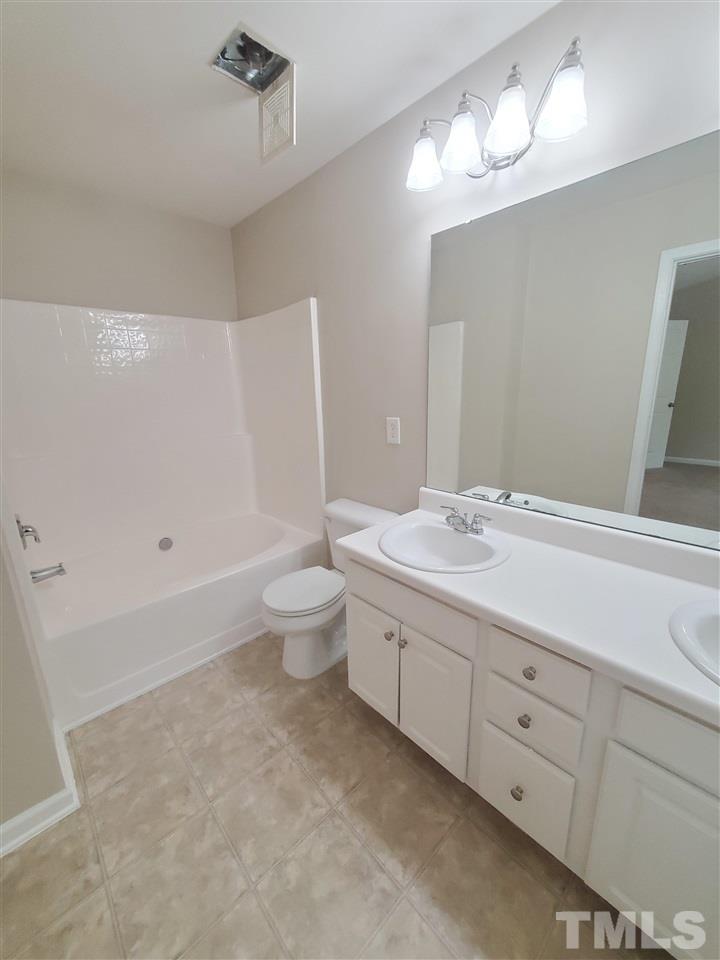 8208 Clasara Circle Raleigh, NC 27613 - Photo 14 of 26 a bathroom with a granite countertop sink a toilet and a mirror