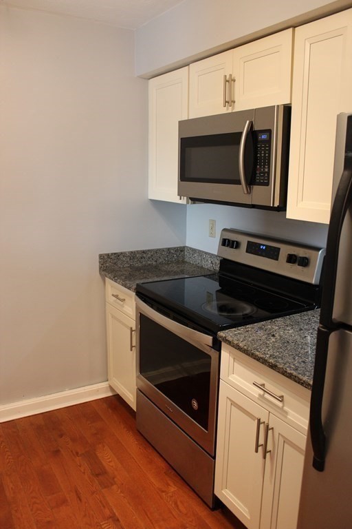 36 C Gibbs Street, Unit 29 Worcester, MA 01607 - Photo 5 of 25 a kitchen with granite countertop a stove and a microwave