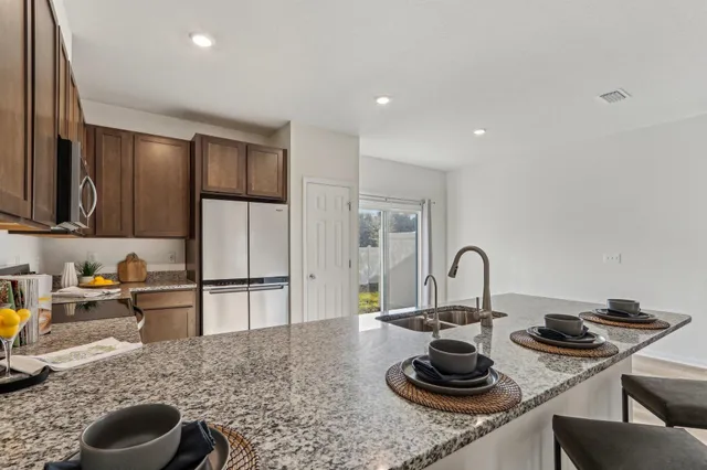 a kitchen with stainless steel appliances granite countertop a sink a stove and refrigerator