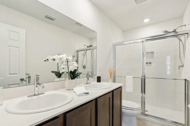 a bathroom with a double vanity sink mirror and toilet