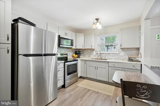a kitchen with granite countertop a refrigerator stove top oven and sink