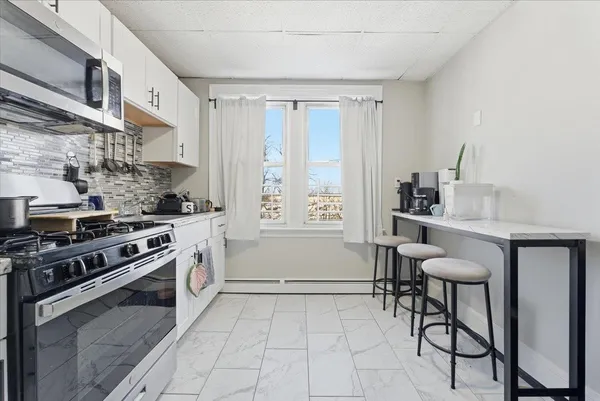 a kitchen with stainless steel appliances a stove a sink and white cabinets