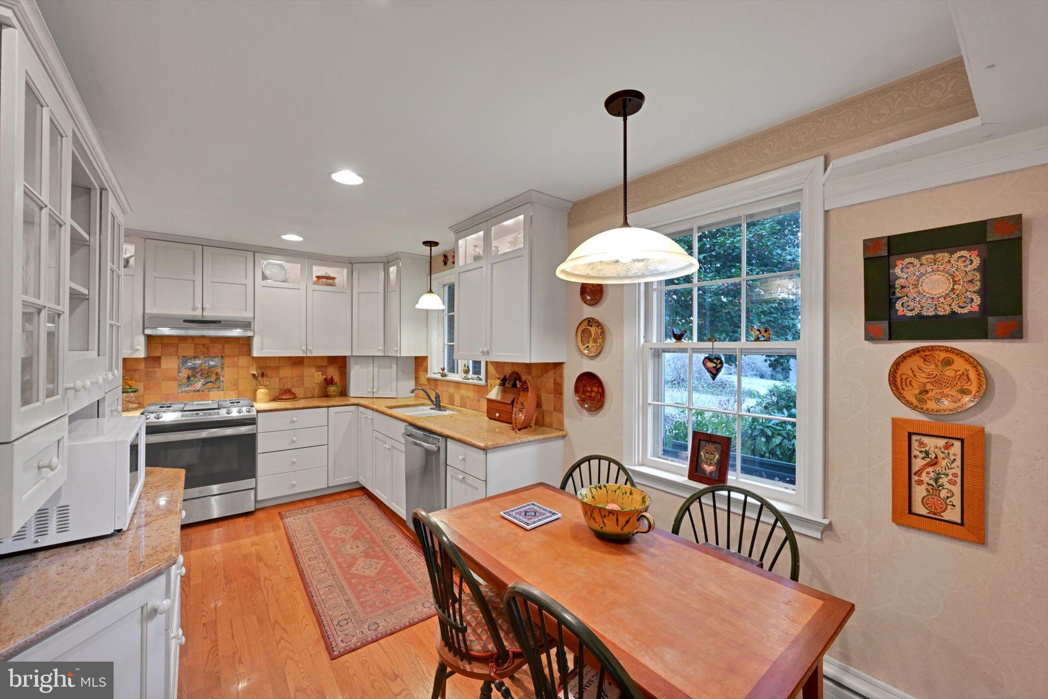 411 Woodcrest Avenue Lititz, PA 17543 - Photo 10 of 38 a kitchen with stainless steel appliances granite countertop a stove top oven a refrigerator a sink a dining table and chairs with wooden floor