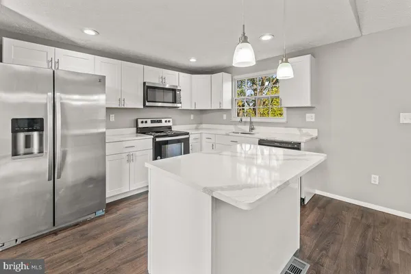 a kitchen with stainless steel appliances granite countertop a sink a refrigerator and a stove top oven