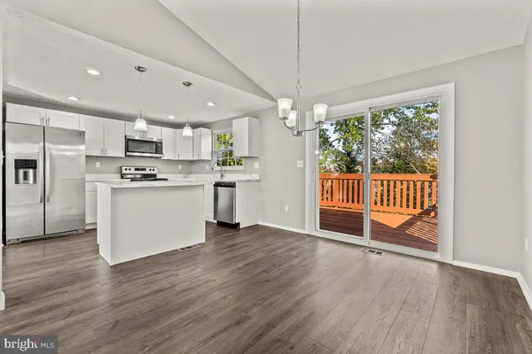 a view of kitchen with stainless steel appliances granite countertop a stove top oven a refrigerator and a wooden floor