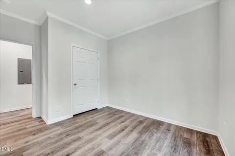 a view of an empty room with wooden floor and closet