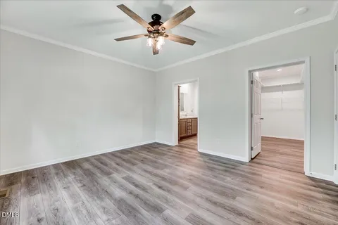 an empty room with wooden floor and ceiling fan