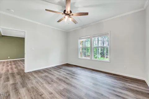 an empty room with wooden floor fan and windows