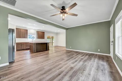 a view of an empty room with wooden floor and a fireplace